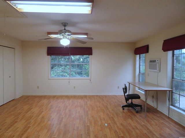 unfurnished office with ceiling fan, a wall mounted air conditioner, and light wood-type flooring