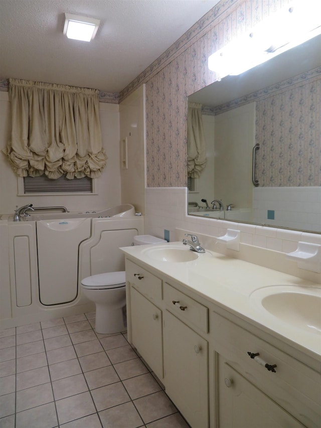 bathroom featuring vanity, a textured ceiling, tile patterned floors, and toilet