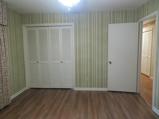 unfurnished bedroom with dark wood-type flooring and a closet