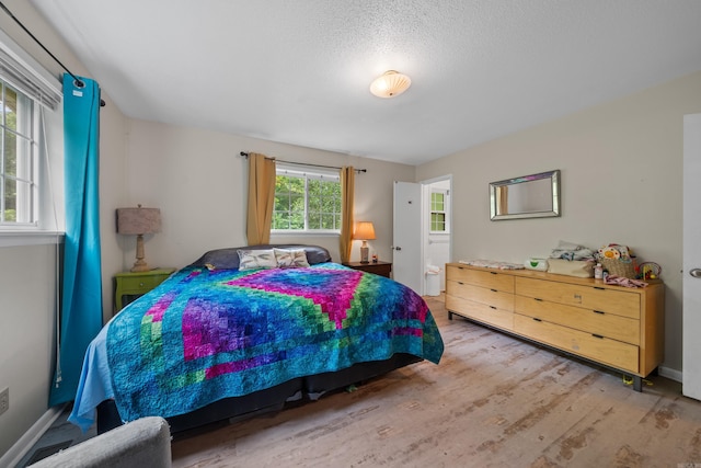 bedroom with a textured ceiling and light wood-type flooring