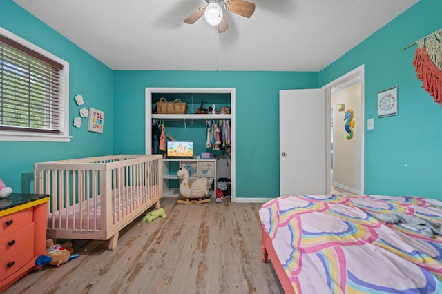 bedroom with ceiling fan, a textured ceiling, light hardwood / wood-style floors, and a closet