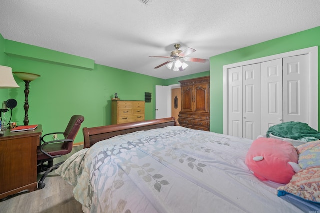 bedroom featuring ceiling fan, light hardwood / wood-style flooring, a closet, and a textured ceiling