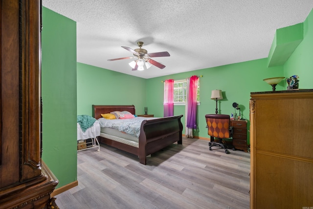 bedroom featuring ceiling fan, light hardwood / wood-style floors, and a textured ceiling