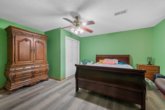 bedroom featuring ceiling fan, light hardwood / wood-style floors, a closet, and a textured ceiling