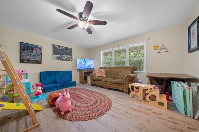 playroom with ceiling fan, hardwood / wood-style floors, and a textured ceiling