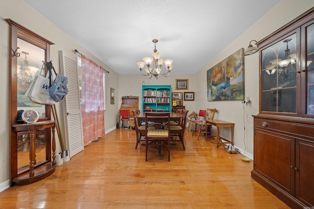 dining space with light hardwood / wood-style floors and a chandelier