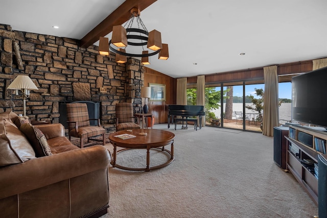 carpeted living room with wooden walls, a stone fireplace, a chandelier, and vaulted ceiling with beams