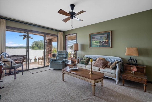 carpeted living room featuring ceiling fan and a water view