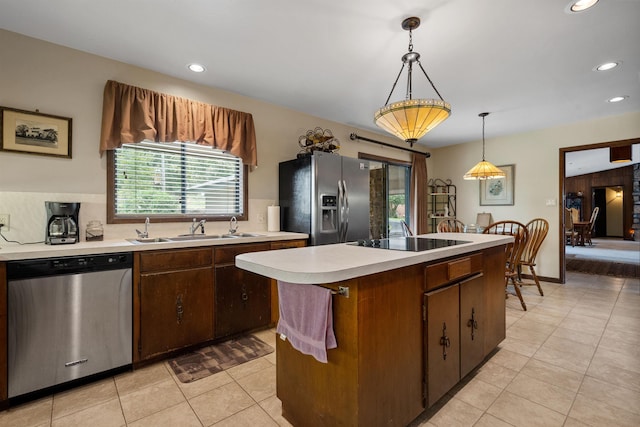 kitchen with light tile patterned floors, stainless steel appliances, hanging light fixtures, a kitchen island, and sink