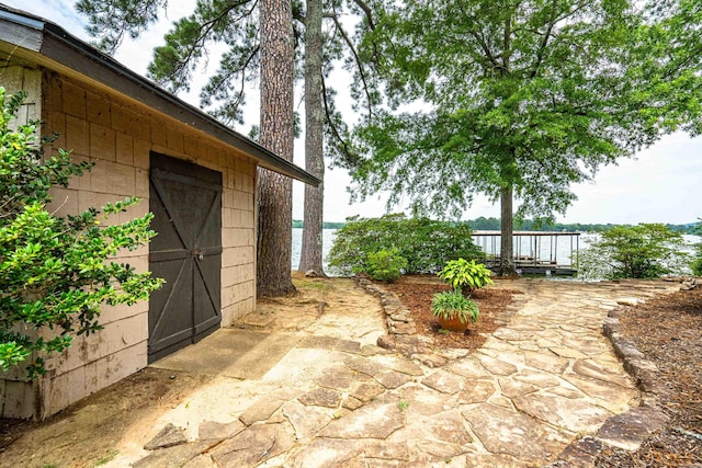 view of patio / terrace with a water view and a storage shed