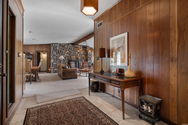 interior space with beam ceiling, wood walls, and a stone fireplace