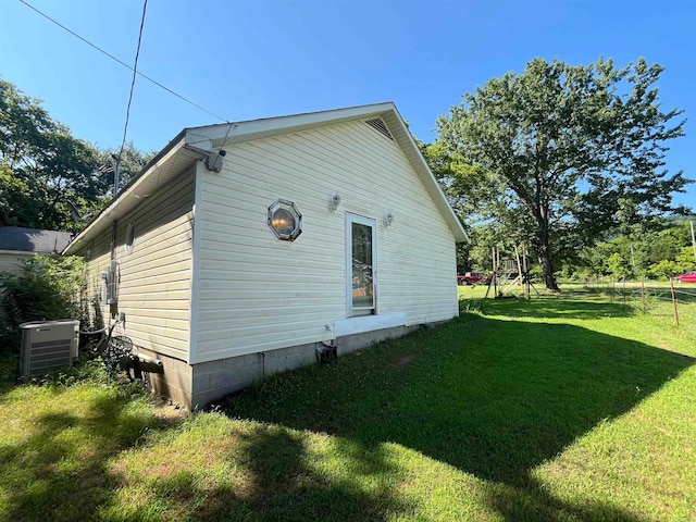 view of side of property featuring a yard and central AC