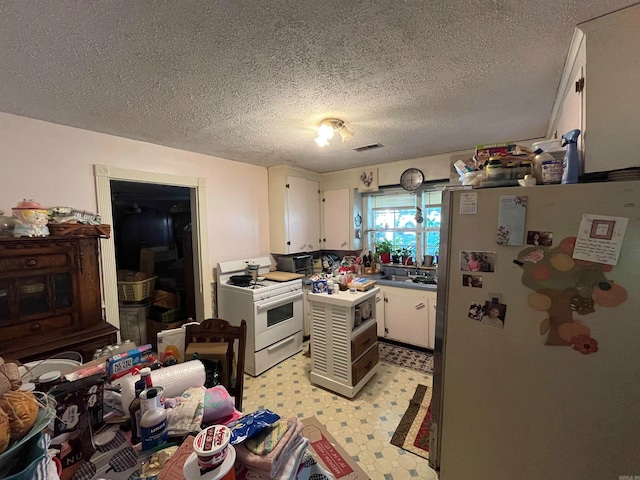 kitchen featuring a textured ceiling, white appliances, white cabinets, sink, and light tile flooring