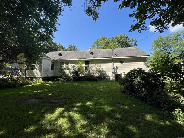 back of property featuring central AC unit and a lawn