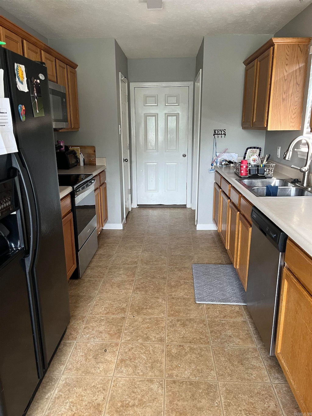 kitchen with appliances with stainless steel finishes, sink, and light tile floors