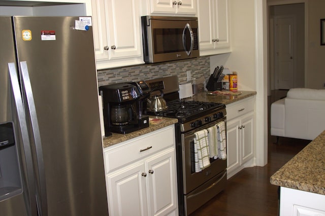 kitchen featuring dark stone counters, white cabinetry, appliances with stainless steel finishes, and tasteful backsplash