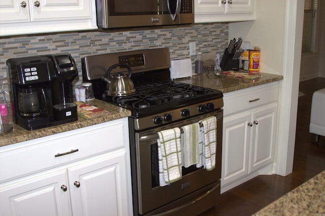 kitchen with white cabinets, decorative backsplash, stainless steel appliances, and stone countertops