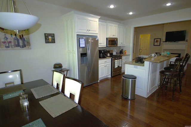 kitchen featuring a center island with sink, white cabinetry, a breakfast bar area, and appliances with stainless steel finishes