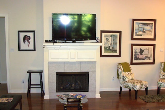 living room featuring dark hardwood / wood-style floors and a tiled fireplace