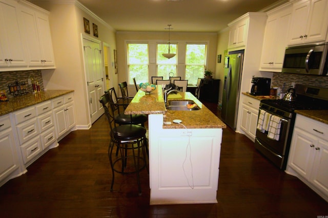 kitchen featuring appliances with stainless steel finishes, a center island with sink, white cabinetry, and sink