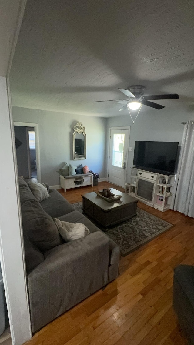 living room with wood-type flooring, ceiling fan, and a textured ceiling