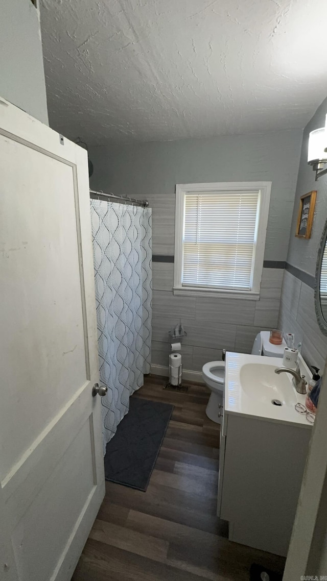 bathroom with wood-type flooring, vanity, toilet, a textured ceiling, and a shower with curtain