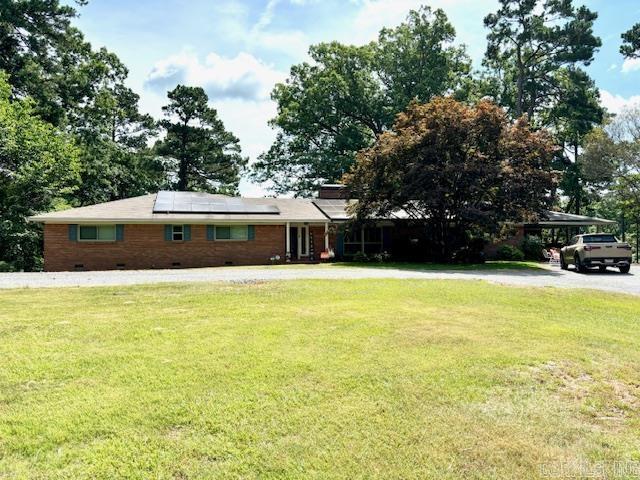 view of front of property featuring a front yard and solar panels