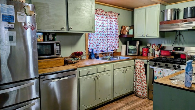 kitchen with wooden counters, stainless steel appliances, sink, light hardwood / wood-style floors, and range hood