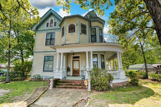 victorian house featuring a front lawn and a porch