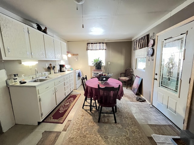 kitchen featuring white electric range oven, white cabinetry, and sink