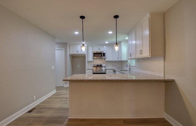 kitchen featuring stainless steel appliances, sink, white cabinets, and kitchen peninsula