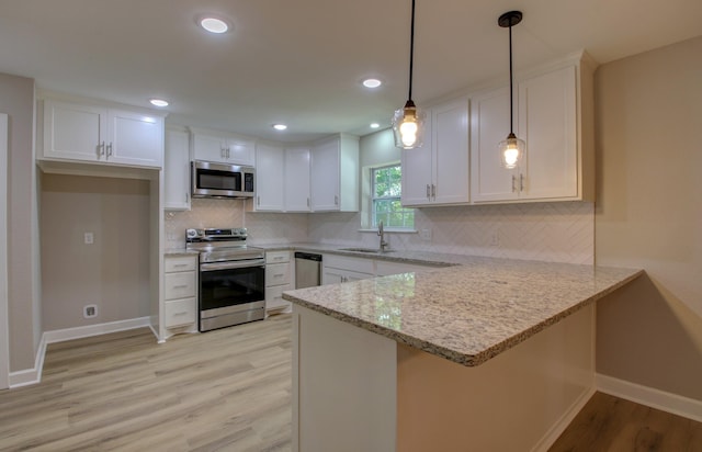 kitchen with white cabinetry, appliances with stainless steel finishes, decorative light fixtures, and kitchen peninsula