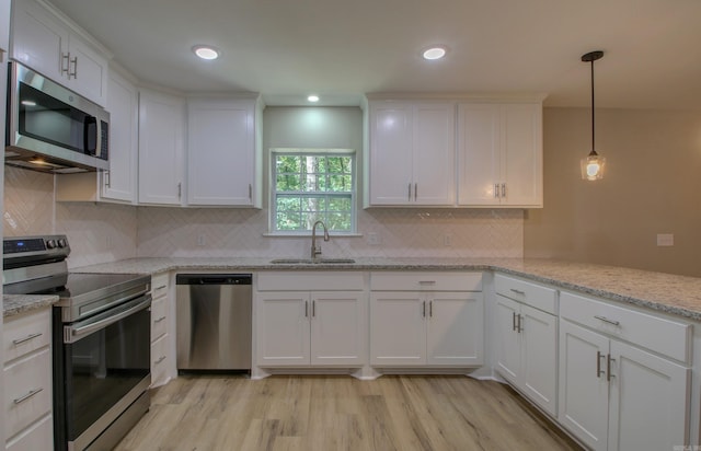 kitchen with pendant lighting, sink, white cabinets, and appliances with stainless steel finishes