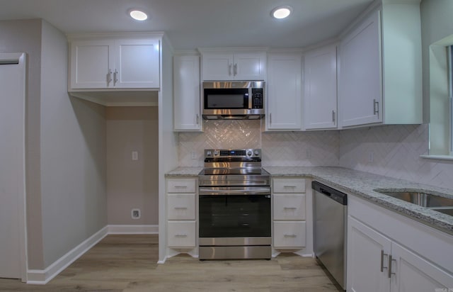 kitchen featuring white cabinetry, light stone counters, and appliances with stainless steel finishes