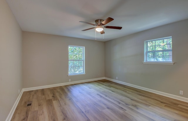 empty room with ceiling fan, plenty of natural light, and light hardwood / wood-style floors