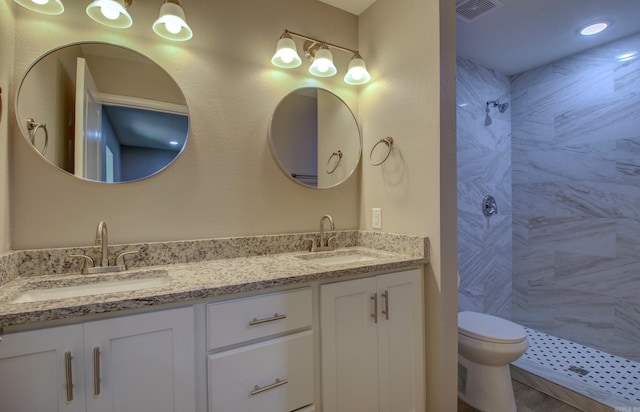 bathroom featuring vanity, toilet, and a tile shower