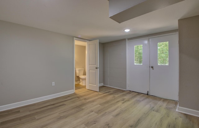 unfurnished bedroom featuring ensuite bathroom and light hardwood / wood-style floors