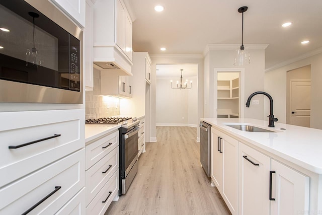 kitchen featuring sink, hanging light fixtures, tasteful backsplash, white cabinets, and appliances with stainless steel finishes