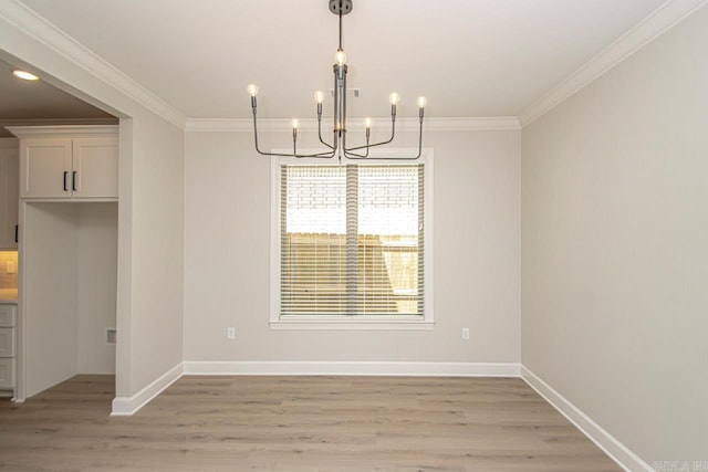 unfurnished dining area featuring crown molding, a notable chandelier, and light wood-type flooring