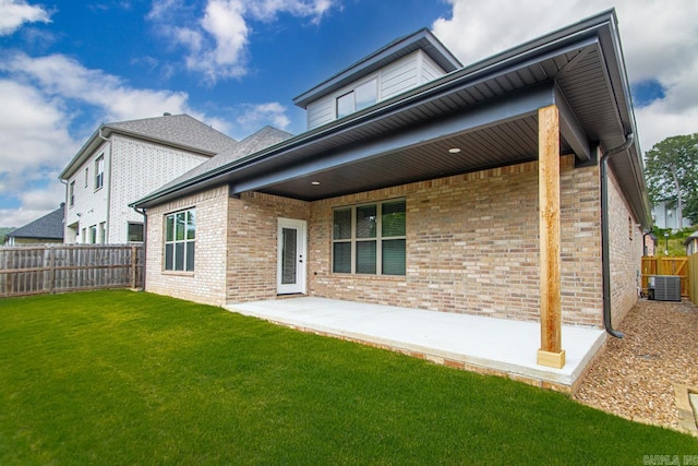 rear view of property featuring central AC unit, a patio area, and a lawn