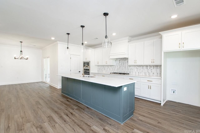 kitchen featuring pendant lighting, white cabinets, sink, an island with sink, and stainless steel gas cooktop