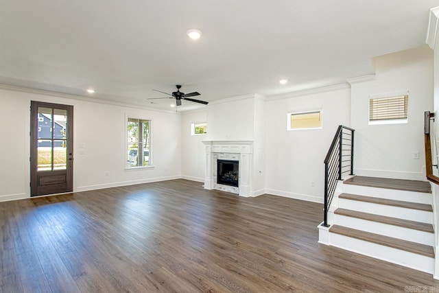 unfurnished living room featuring dark hardwood / wood-style flooring, ceiling fan, ornamental molding, and a premium fireplace