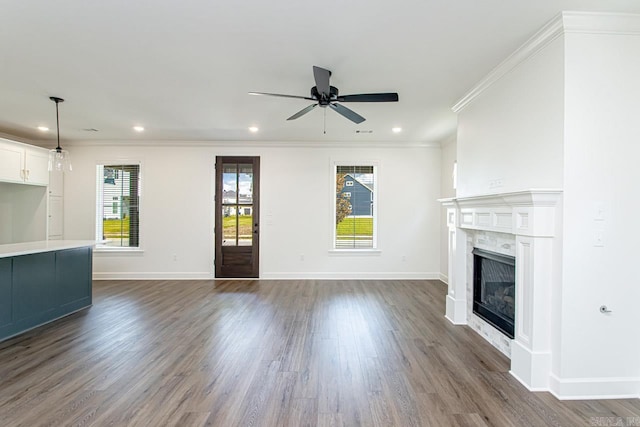 unfurnished living room featuring ceiling fan, dark hardwood / wood-style flooring, ornamental molding, and a high end fireplace