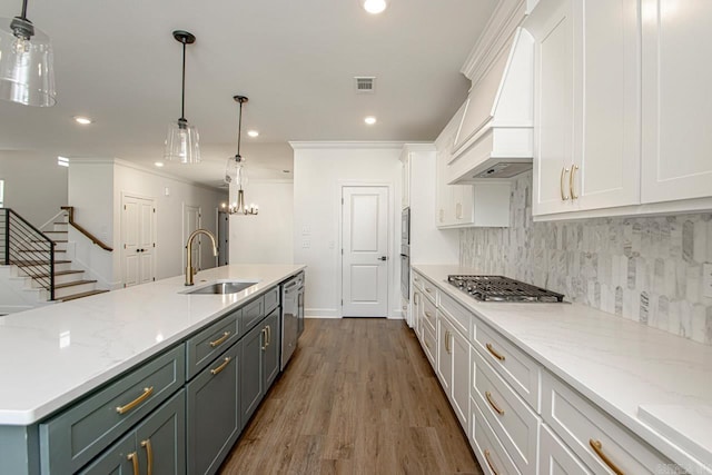 kitchen with white cabinetry, sink, premium range hood, a kitchen island with sink, and appliances with stainless steel finishes