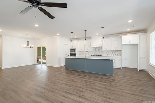 kitchen with a center island with sink, white cabinets, and decorative light fixtures