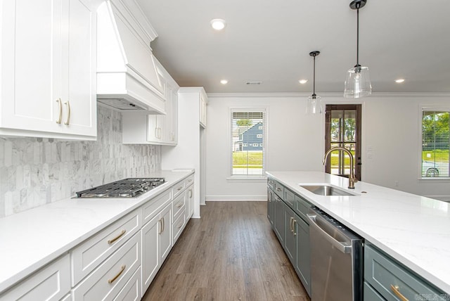 kitchen featuring white cabinetry, sink, decorative light fixtures, custom range hood, and appliances with stainless steel finishes