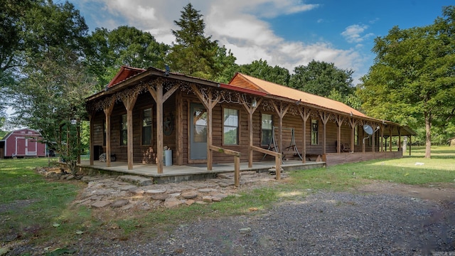 view of front facade with covered porch, a shed, and a front lawn