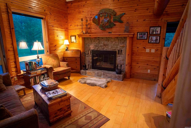 living room with a stone fireplace, wood walls, and hardwood / wood-style floors