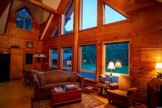 living room featuring beam ceiling, hardwood / wood-style flooring, wood walls, and high vaulted ceiling