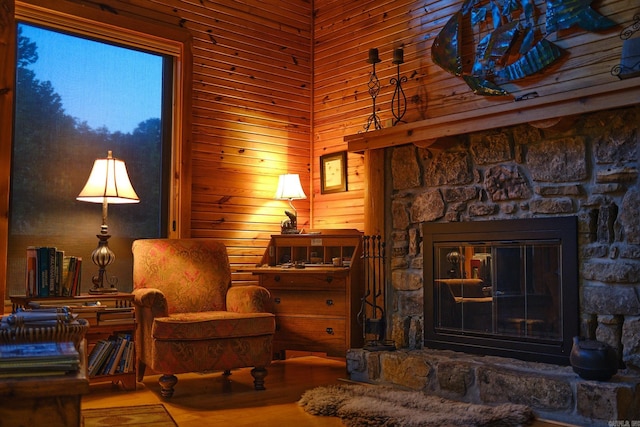 living room with a stone fireplace, wood walls, and wood-type flooring